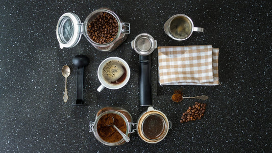 Top view of coffee brewing setup with beans, cup, and accessories on black granite.